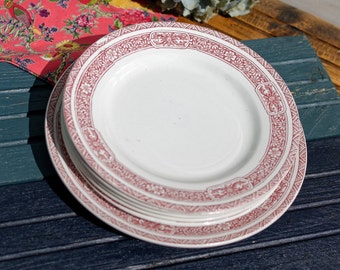 May include: A stack of six white ceramic plates with a red floral pattern around the rim.