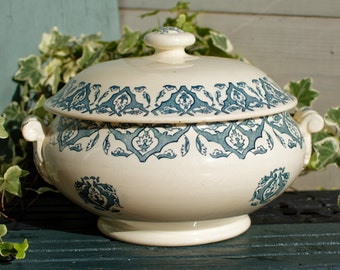 May include: A white ceramic serving dish with a blue and white floral pattern. The dish has a lid and two handles.