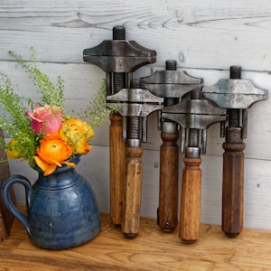 May include: Five vintage adjustable wrenches with wooden handles. The wrenches are made of metal and have a silver finish. The handles are a dark brown color.