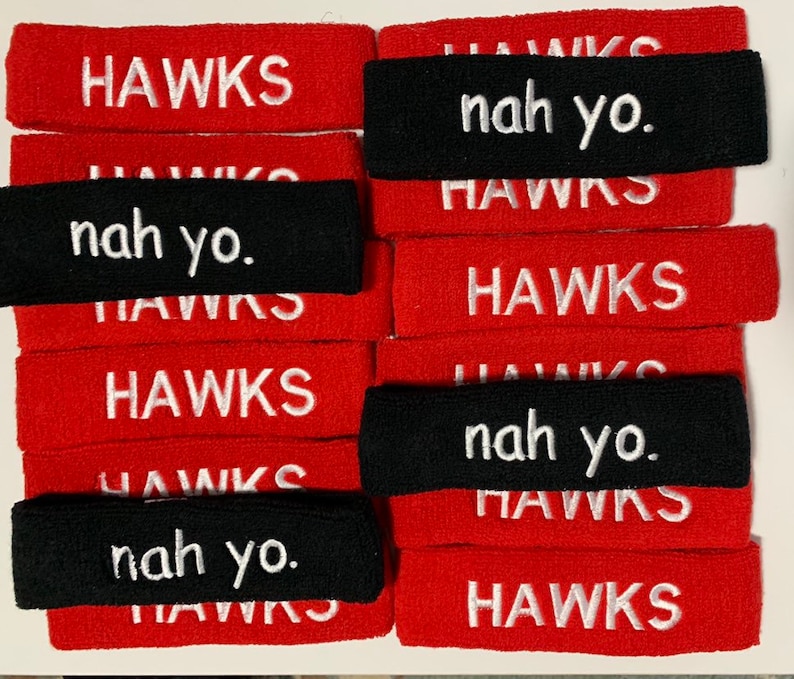 May include: A collection of red and black headbands. The red headbands have the word "HAWKS" embroidered in white. The black headbands have the phrase "nah yo." embroidered in white.
