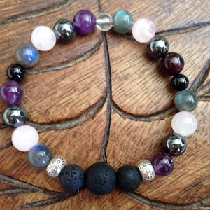 May include: A bracelet made with various gemstones, including amethyst, rose quartz, labradorite, and haematite. The bracelet also features two black lava beads and silver spacer beads.