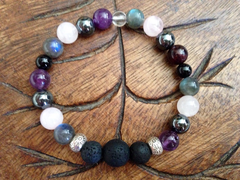 May include: A bracelet made with various gemstones, including amethyst, rose quartz, labradorite, and haematite. The bracelet also features two black lava beads and silver spacer beads.