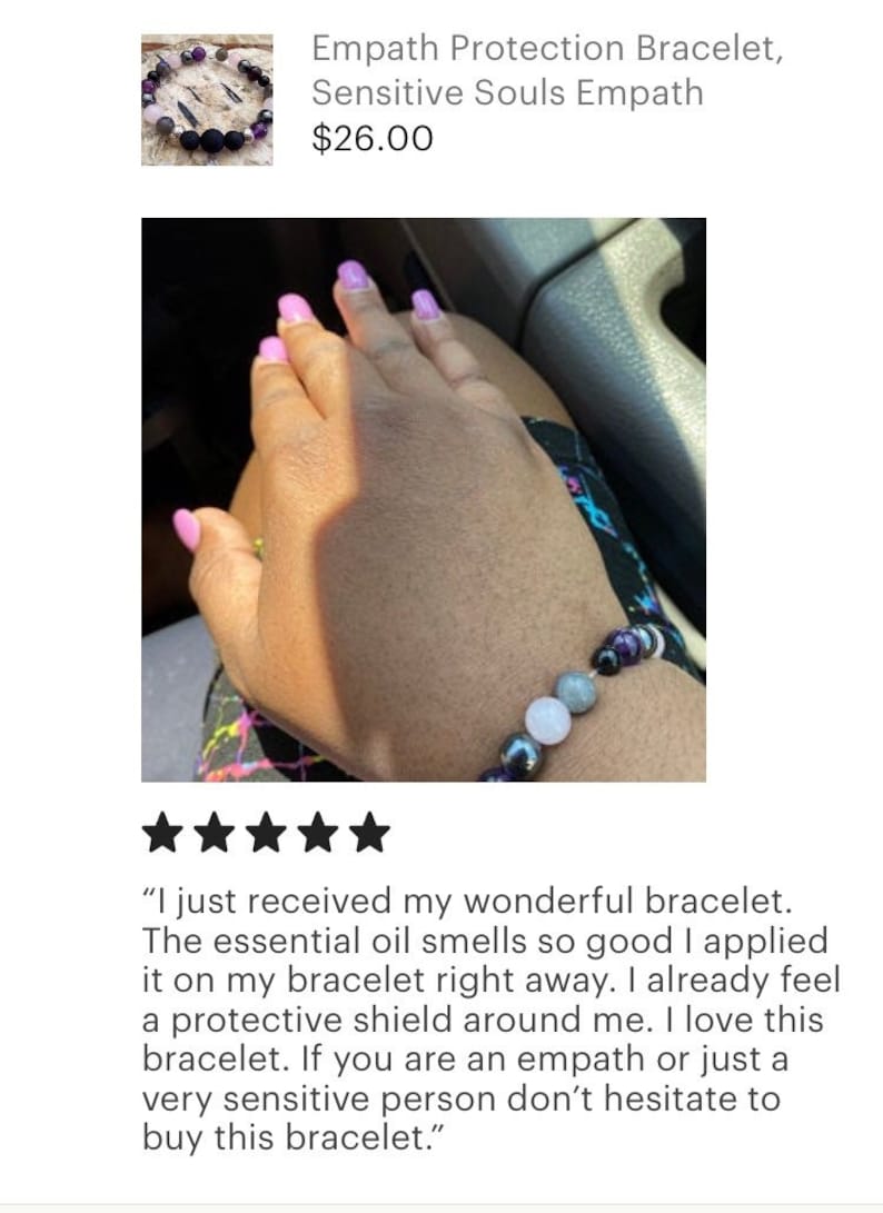 May include: A close-up of a person's wrist wearing a beaded bracelet with purple, black, grey, and white stones. The bracelet is described as an "Empath Protection Bracelet" and is said to provide a "protective shield".
