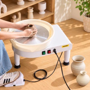 Pode incluir: Uma roda de oleiro elétrica branca com um disco giratório de metal, uma bacia de proteção bege removível e o logótipo VEVOR. A máquina possui um interruptor verde, um interruptor vermelho e um cabo preto ligado a um pedal de controlo.