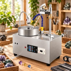 Puede incluir: Una máquina de facetado de piedras preciosas de acero inoxidable con un disco de pulido circular, una lámpara LED flexible, una boquilla de refrigerante azul y amarilla, y un mástil vertical con medidor de ángulo. Panel de control digital.