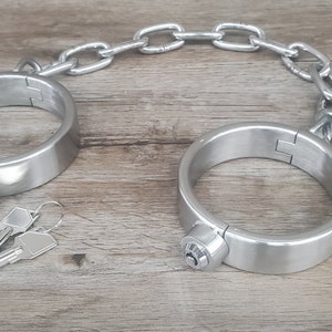 May include: A pair of silver metal handcuffs with a chain connecting them. Two keys are included.