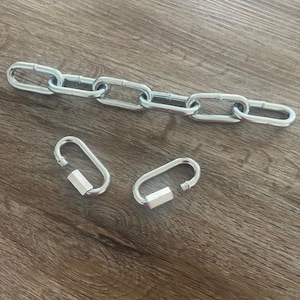 Könnte beinhalten: Zwei silberne Metall-Schnellverschlüsse und eine silberne Kette mit mehreren ovalen Gliedern.