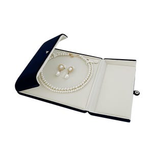 May include: A navy blue velvet jewelry box with a white interior, open to reveal a pearl necklace and matching earrings.