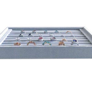 May include: A light blue velvet jewelry display tray filled with various rings. The rings feature different designs and gemstones, including diamonds and colorful stones. The tray is rectangular with multiple grooves to hold the rings.