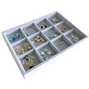 May include: A gray velvet jewelry tray with 12 compartments, filled with various jewelry pieces, including earrings, rings, and necklaces.