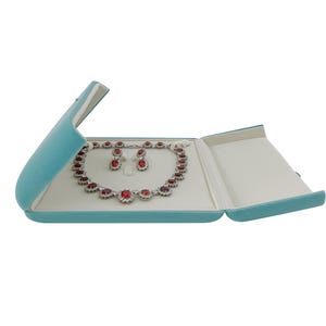 May include: A turquoise velvet jewelry box with a red and white gemstone necklace and earrings inside.