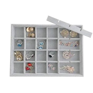 May include: A gray velvet jewelry organizer with multiple compartments, holding various rings, earrings, and bracelets. The organizer has a removable lid and is designed to store and display jewelry. The jewelry includes gold, silver, and gemstone pieces.