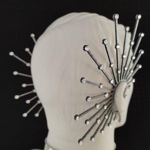May include: A pair of silver ear cuffs with a starburst design. Each cuff is adorned with small, clear rhinestones.