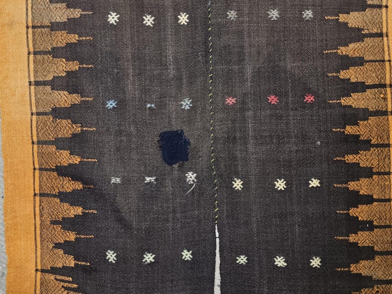 May include: A black and brown woven rug with a geometric pattern. The rug has a fringe border and is made of wool.