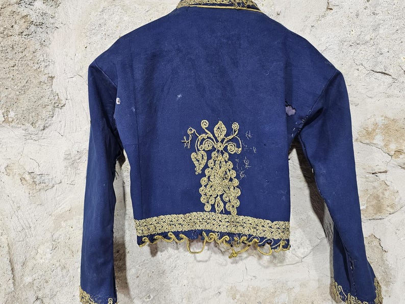 K&ouml;nnte beinhalten: Eine marineblaue Vintage-Jacke mit goldener Stickerei. Die Jacke hat aufwendige goldene Blumenstickereien auf dem R&uuml;cken und an den Kanten. Lange &Auml;rmel und ein robuster Stoff sind sichtbar. Historisches Kleidungsst&uuml;ck.