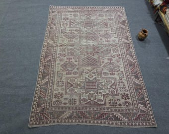 May include: A rectangular area rug featuring a faded, muted red and beige color palette with intricate geometric patterns, including central star motifs, stepped diamonds, and a detailed border with repeating angular shapes and linear designs.