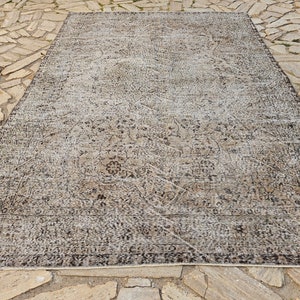 May include: A vintage-style rug with a faded, distressed look. The rug has a light beige background with a dark brown floral pattern.