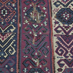 May include: A woven textile featuring vertical panels with repeating geometric patterns in shades of deep blue, magenta, and cream. The design includes stylized diamond shapes and symmetrical motifs arranged in a dense, intricate, and textured weave.
