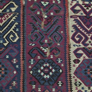 May include: A woven textile featuring three vertical panels with geometric patterns. The left panel is dark blue, the center is deep magenta, and the right is off-white. Each section displays repeating angular motifs and octagonal shapes.