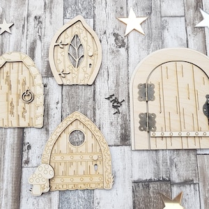 May include: Five wooden fairy doors with different designs, including a leaf, a keyhole, and a simple door. The doors are on a woodgrain background.
