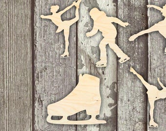 May include: Five wooden cutouts of ice skaters and a skate. The cutouts are in various poses and are all facing the same direction. The cutouts are on a wooden background.