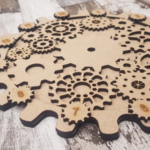 May include: A wooden gear puzzle with numbers 1 through 10 on the outer ring. The gears are interlocked and can be rotated to solve the puzzle.