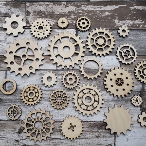 May include: A collection of wooden gears of various sizes and shapes, arranged in a decorative pattern on a light brown wood background.