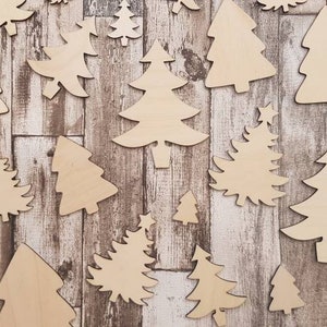 Pode incluir: Uma coleção de formas de árvores de Natal de madeira em vários tamanhos, dispostas sobre um fundo de madeira rústica. As árvores não são pintadas e estão prontas para a elaboração.