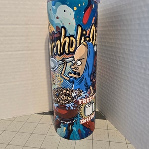 May include: A blue and red tumbler with a cartoon character holding a spoon and a bowl of cereal. The text "The Great Cornholio" is printed on the tumbler. The text "Free Toilet Paper Inside" is also printed on the tumbler.