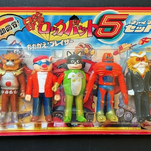 May include: A vintage, unopened toy set featuring five colorful action figures. The figures include a pig in a red jacket, a cat-like character in a green suit, and a robot. The packaging is red and yellow with Japanese text.