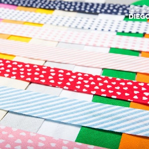 May include: A collection of colourful fabric ribbon trims with various patterns, including polka dots, stripes, and hearts. The ribbons are arranged in a layered pattern, creating a visually appealing display.