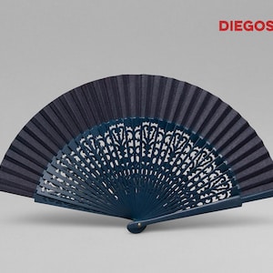 May include: A dark blue hand fan with a decorative, intricate, carved design. The fan is made of wood and fabric.