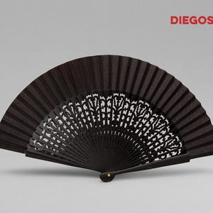 May include: A black hand fan with a decorative, intricate, cut-out design. The fan is closed and has a black fabric covering.