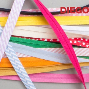 May include: A variety of colorful fabric trims, including striped, polka dot, and solid colors. The trims are arranged in a criss-cross pattern and the word "DIEGOS" is visible in the top right corner.