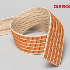 Puede incluir: Banda el&aacute;stica naranja y crema con un patr&oacute;n tejido. La banda est&aacute; doblada por la mitad y el nombre de la marca "DIEGOS" es visible en la esquina superior derecha.