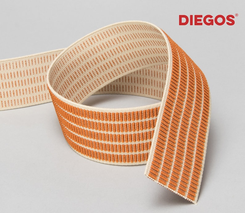 Puede incluir: Banda el&aacute;stica naranja y crema con un patr&oacute;n tejido. La banda est&aacute; doblada por la mitad y el nombre de la marca "DIEGOS" es visible en la esquina superior derecha.