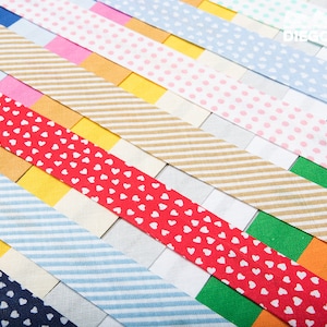 May include: Assortment of colourful patterned washi tapes. The tapes feature various designs, including stripes, polka dots, and hearts.