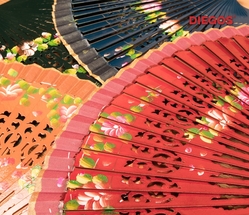 May include: Three hand fans with painted floral designs. The top fan is black with gold trim, the middle fan is orange with gold trim, and the bottom fan is red with gold trim. The fans are folded and have a decorative cut-out design.