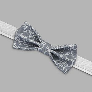 May include: A gray bow tie with a white floral pattern. The bow tie is tied and ready to wear.