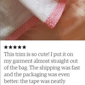 May include: White cotton fabric with a pink heart trim. The fabric has a delicate eyelet pattern.