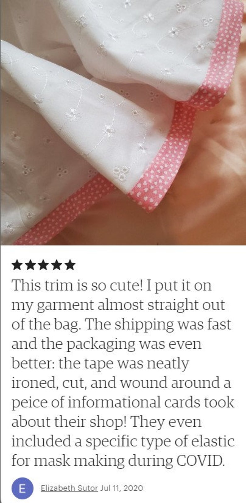 May include: White cotton fabric with a pink heart trim. The fabric has a delicate eyelet pattern.