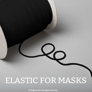 May include: A spool of black elastic cord for making face masks. The elastic is wound around a cardboard spool and a length of the elastic is lying on a gray surface.