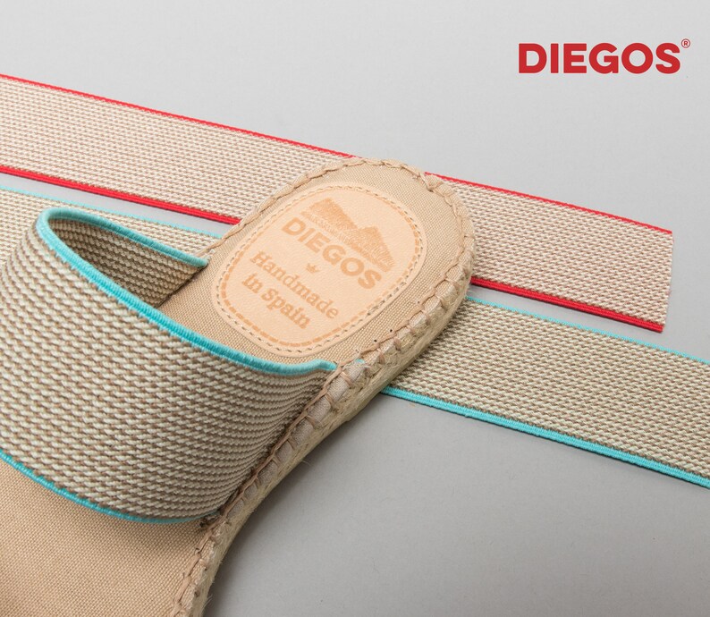 May include: Beige espadrille sandals with a blue elastic strap and a brown leather label that reads "DIEGOS Handmade in Spain".