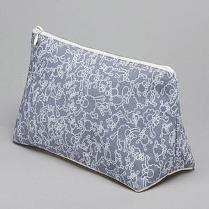 May include: A gray zippered pouch with a white pattern of small animals. The pouch is made of a soft, fabric material.