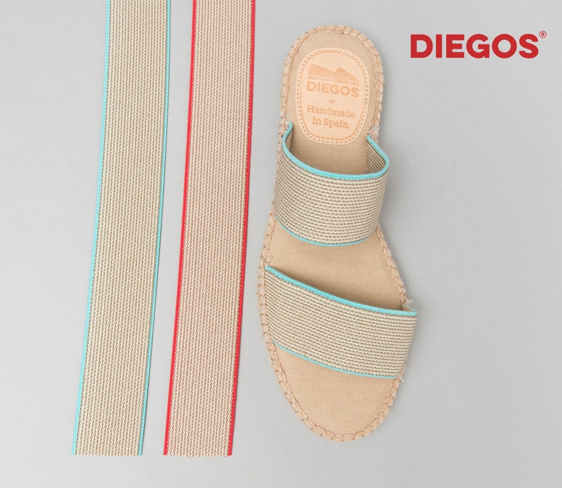May include: Two beige fabric straps with a blue and red trim. A pair of beige espadrille sandals with a blue trim and a leather label that reads "DIEGOS Handmade in Spain".