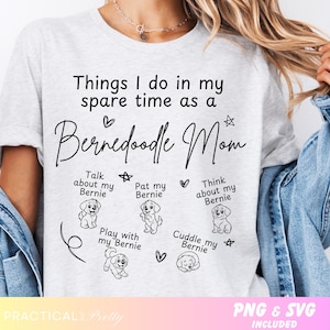 May include: A light gray t-shirt with the text "Things I do in my spare time as a Bernedoodle Mom." The shirt features illustrations of Bernedoodle dogs and phrases like "Talk about my Bernie" and "Cuddle my Bernie."