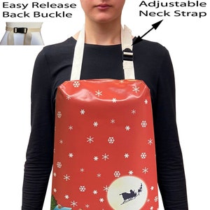May include: A red Christmas-themed apron featuring a winter scene with snowmen, a house, and a Christmas tree. The apron has an adjustable neck strap and an easy-release back buckle.