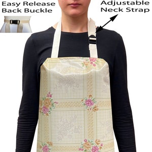 May include: A beige apron with a floral pattern and adjustable neck strap. The apron has an easy release back buckle.