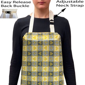 May include: A yellow and blue checked apron with a heart pattern. The apron has an adjustable neck strap and an easy release back buckle.