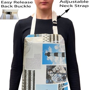 May include: A white apron featuring a colourful lighthouse and seashell design. The apron has an adjustable neck strap and an easy release back buckle.
